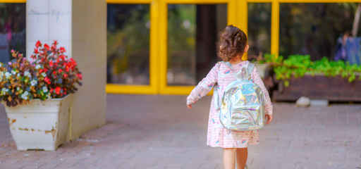 little girl walking to preschool with backpack