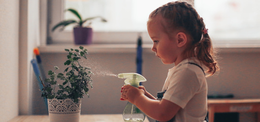 Toddler taking care of plants spraying water with bottle